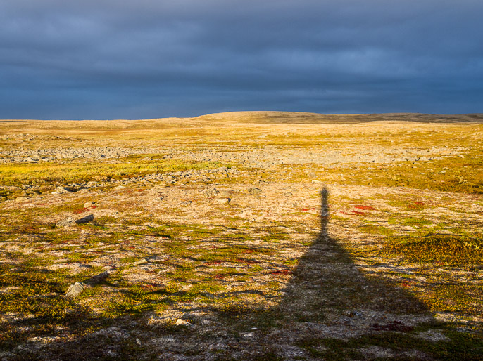 Kiva ilta-aurinko seistä ympäristön suurimman kiven päällä, mutta epäilyttävän tummat pilvet ovat kerääntymässä. Gottetjavrrit, Norja