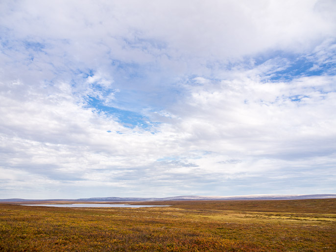 Järven alapuolelta oikealla kaartaen, kaukaisuudessa valkoista heijastavat kivikasat. Suovvejavri, Norja